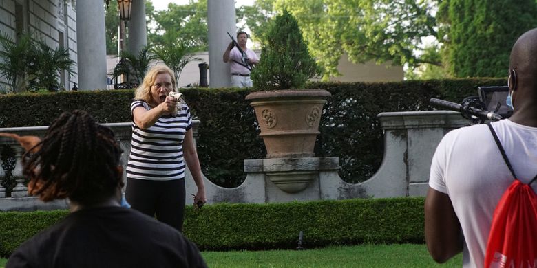 Seorang perempuan menodongkan pistol ke arah pengunjuk rasa yang hendak memasuki rumahnya dalam aksi menentang Wali Kota St Louis, Lyda Krewson, Missouri, Amerika Serikat (AS), pada 28 Juni 2020.