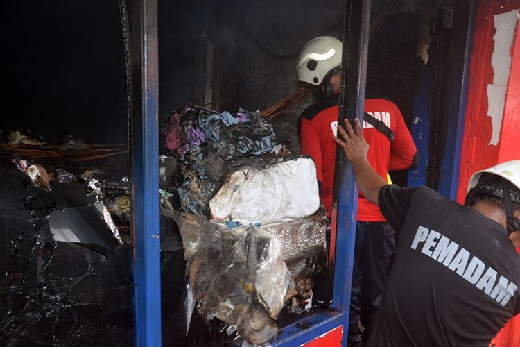 Petugas pemadam kebakaran memadamkan sisa-sisa api di gudang penyimpanan paket barang kantor cabang JNE di Ternate, Maluku Utara, Senin (27/12/2021)