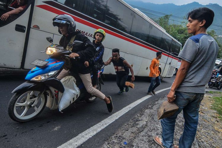 Seorang tukang ganjal mendorong sepeda motor yang tidak kuat nanjak saat melintas pada arus balik H+2 Lebaran di Tanjakan Gentong, Kabupaten Tasikmalaya, Jawa Barat, Jumat (7/6/2019).