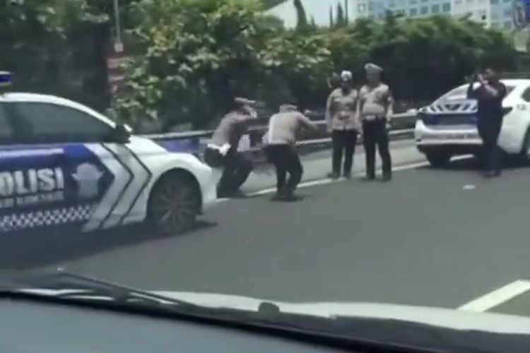 Dua anggota polisi tengah squat jump di dekat Gerbang Tol (GT) Slipi 1, Slipi, Palmerah, Jakarta Barat, Senin (21/10/2024).  