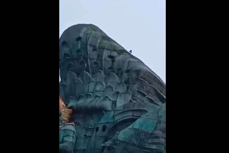 Tangkapan layar video viral seorang pria berdiri di atas patung GWK