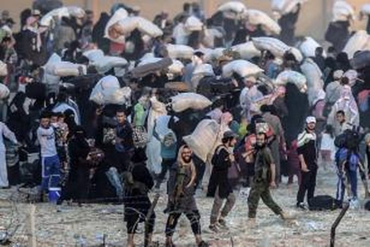 Anggota Negara Islam meminta orang untuk kembali ke pusat kota di pintu perbatasan Turki Akcakale di Provinsi Sanliurfa, 13 Juni 2015. Turki mengatakan pihaknya mengambil langkah-langkah untuk membatasi arus pengungsi perang Suriah.