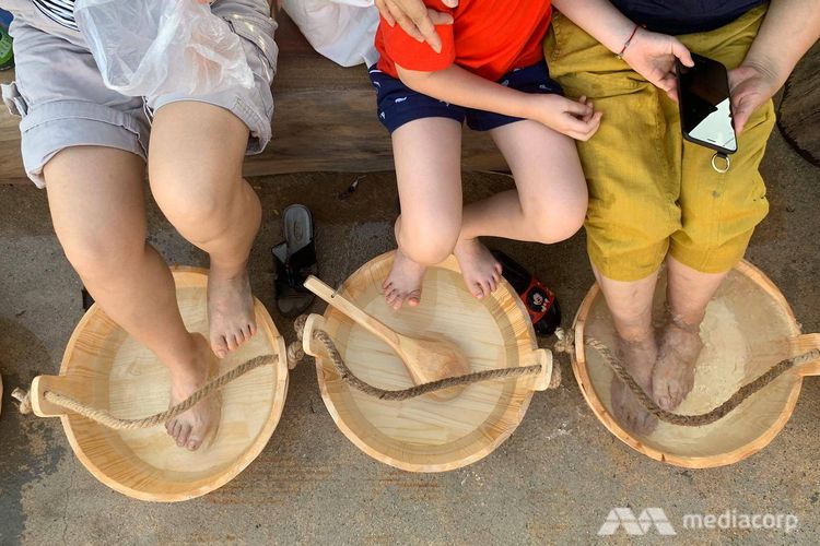 Pengunjung merendam kakinya dalam wadah berisi air panas di Sembawang Hot Spring Park, Singapura.