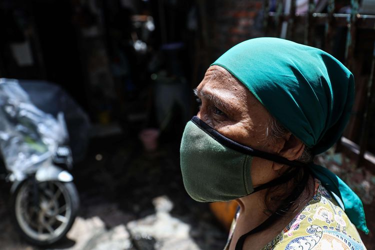 Seorang warga menggunakan masker berdiri didepan rumahnya di Jalan Tambora RT 01/07, Kelurahan Tambora, Jakarta Barat, Rabu (1/4/2020). Sejumlah kelurahan di Ibu Kota mulai menutup akses jalan untuk mencegah penyebaran virus corona atau  COVID-19.