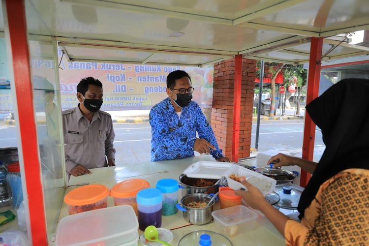 Seorang aparatur sipil negara (ASN) Pemerintah Kota (Pemkot) Madiun sementara berbelanja makanan yang dijual pelaku usaha mikro kecil menengah (UMKM).