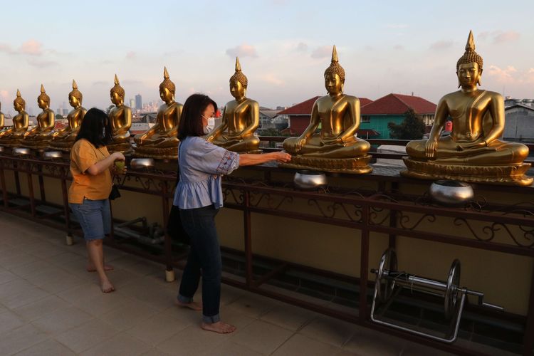 Umat memasukkan uang koin di depan patung Budha di Vihara Hemadhiro Mettavati, Cengkareng, Jakarta Barat, Rabu (26/5/2021). Umat Budha merayakan Hari Tri Suci Waisak.