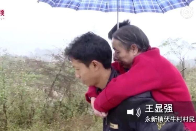 Wang Xianqiang (37) selalu menggendong ibunya, Tian Jinggui, yang lumpuh, saat mencari kerja selama 15 tahun terakhir.