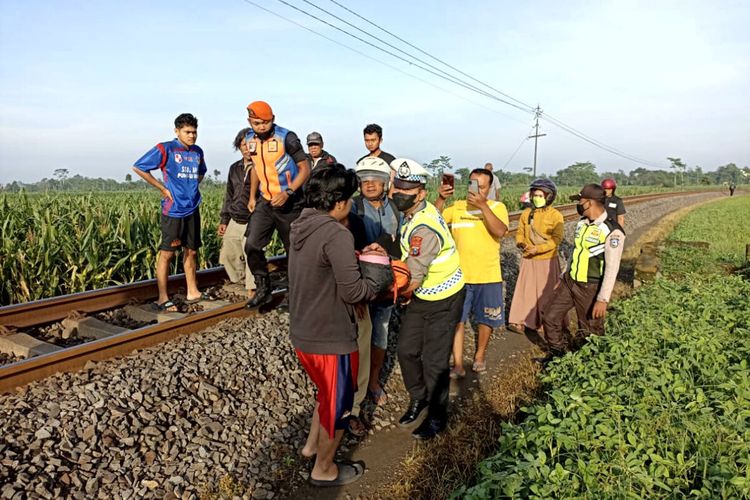Warga dan personel kepolisian menggotong tubuh Sugiati (36) usai tertabrak kereta api di Kelurahan Tangkil, Kecamatan Wlingi, Kabupaten Blitar, Senin (14/11/2022)