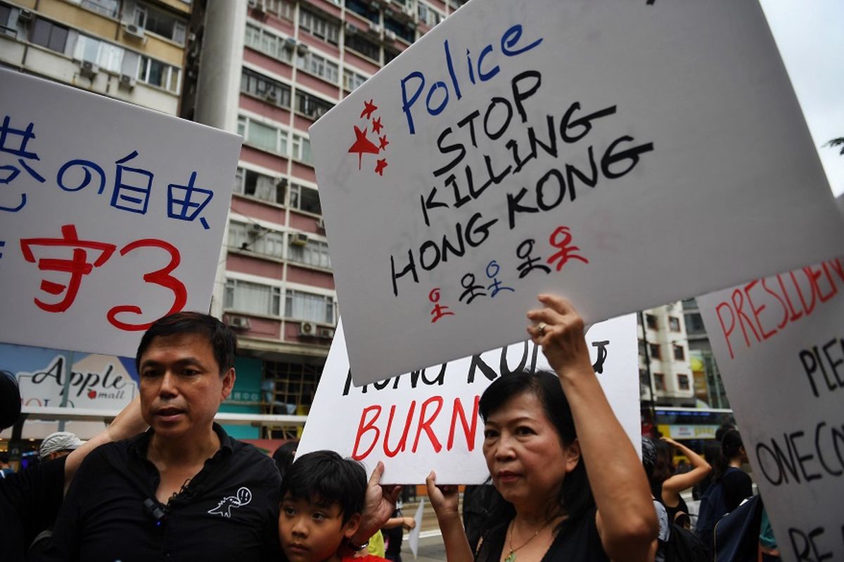 Massa pengunjuk rasa membawa plakat dalam aksi demo di Hong Kong, Minggu (18/8/2019).