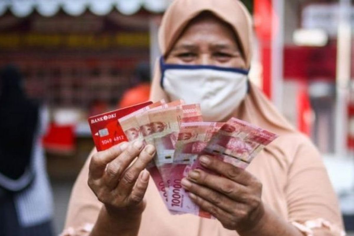 Warga menunjukkan uang bantuan sosial tunai atau BST usai mengambil di ATM Bank DKI, Jakarta, Selasa (20/7/2021).