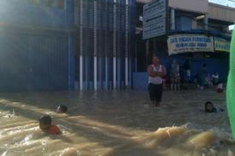 Warga sedang berenang di tengah banjir di Samarinda.