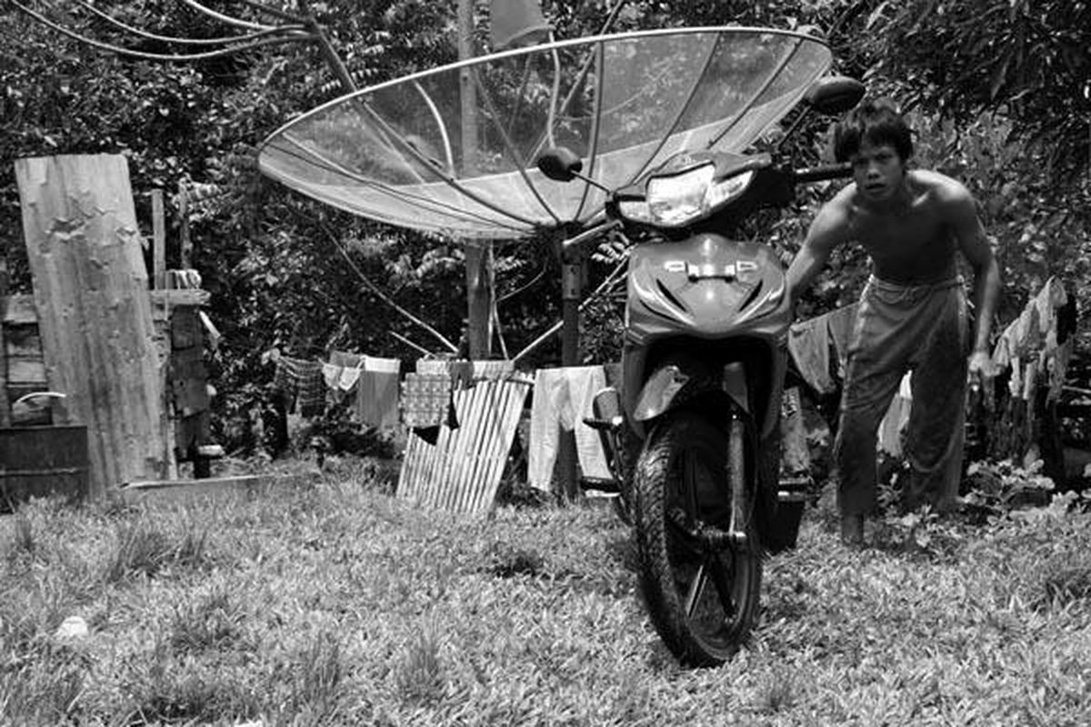 Petani  karet, Budi Susanto (28), mencuci sepeda motor yang baru saja dibeli dari hasil kebun karetnya di Desa Bandar Jaya, Kecamatan Batanghari Leko, Kabupaten Musi Banyuasin, Sumatera Selatan, Selasa (5/4) lalu.