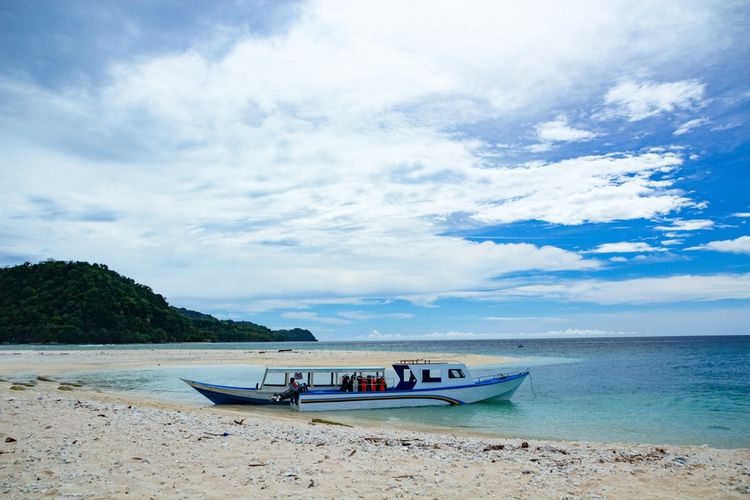 white clear beach of Nailaka island, Banda Islands, diving boat and people on board