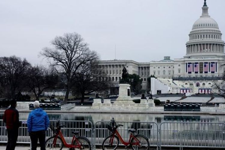 Sejumlah turis menyaksikan Gedung Capitol yang tengah disiapkan untuk prosesi pelantikan presiden baru AS, Jumat (20/1/2017).