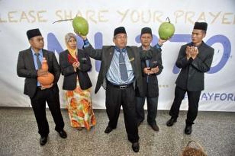 Paranormal atau di Malaysia disebut bomoh, Ibrahim Mat Zin (tengah), Rabu (12/3/2014) di Bandara Internasional Kuala Lumpur, menggelar ritual untuk mencari keberadaan Malaysia Airlines MH370 yang hilang sejak Sabtu (8/3/2014) dalam perjalanan dari Kuala Lumpur menuju Beijing.