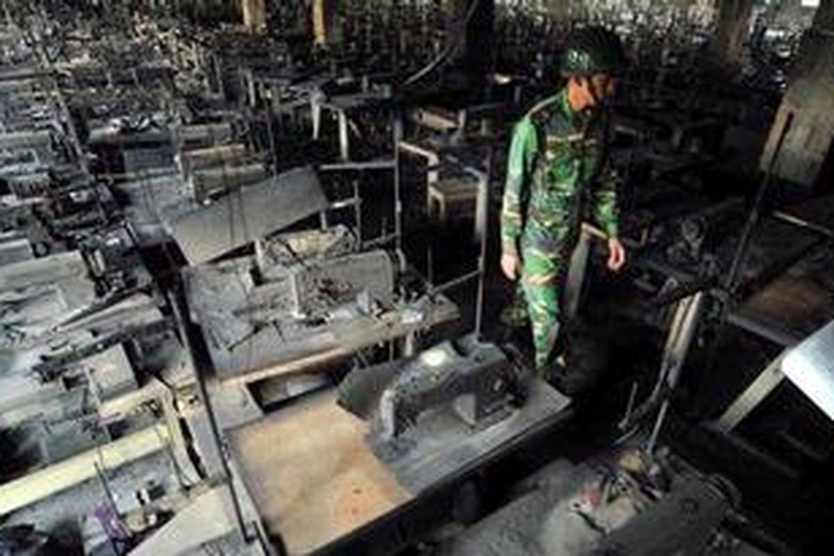 Seorang anggota tentara Banglades berjalan di antara mesin jahit yang hangus dalam kebakaran pabrik garmen akhir pekan lalu yang menewaskan 112 orang pekerjanya.