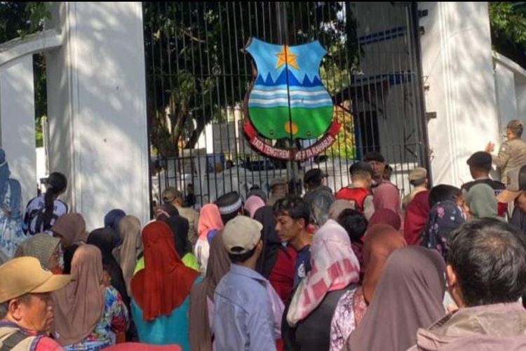 Warga mengantre di gerbang pendopo Garut menunggu gelaran makan gratis yang merupakan rangkaian kegiatan pernikahan Wakil Bupati Garut Putri Karlina dan Maula Akbar putra dari Gubernur Jawa Barat Dedi Mulyadi, Jumat (18/7/2025) siang. 3 orang tewas berdesakan sat mengantre makan gratis ini. 