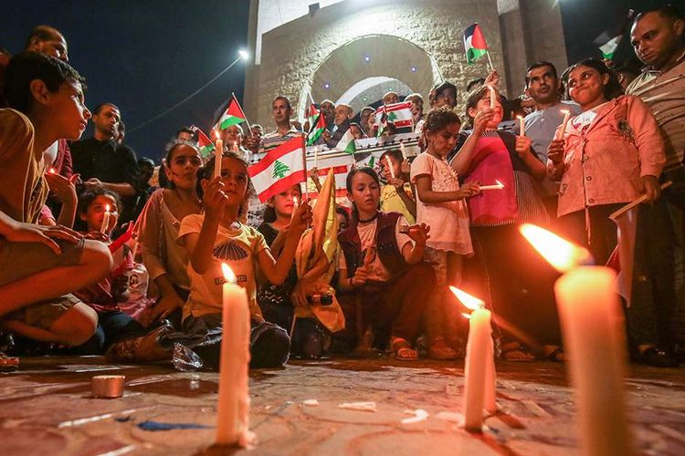 Sejumlah warga Palestina berkumpul menyalakan lilin di Rafah, Jalur Gaza Selatan, Palestina, saat acara solidaritas atas insiden ledakan di Lebanon, Rabu (5/8/2020). Ungkapan duka dan solidaritas mengalir dari berbagai penjuru dunia atas insiden ledakan dahsyat di Beirut, Lebanon, Selasa (4/8/2020), yang menewaskan lebih dari seratus orang.