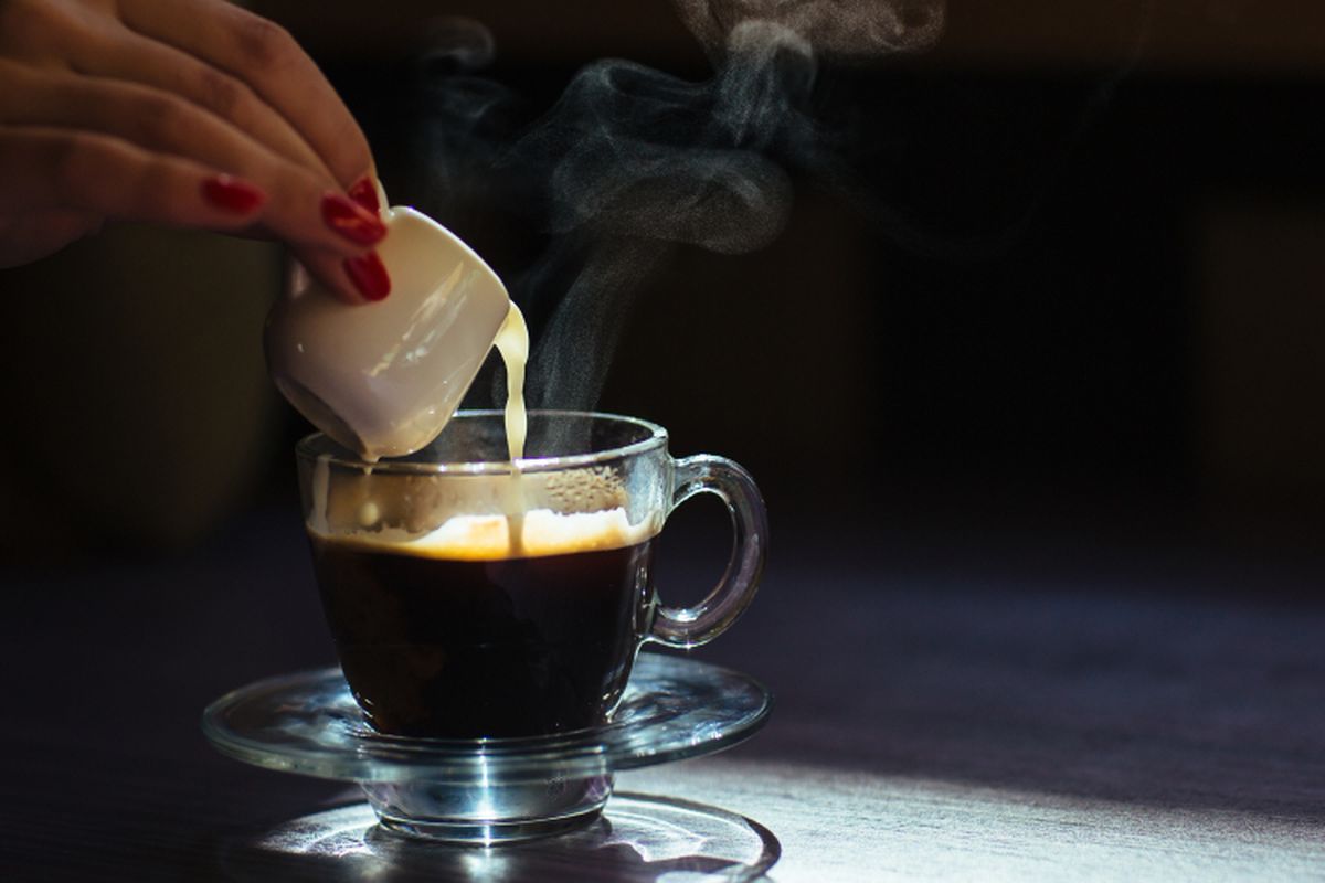 Ilustrasi menambahkan susu ke dalam secangkir kopi panas.