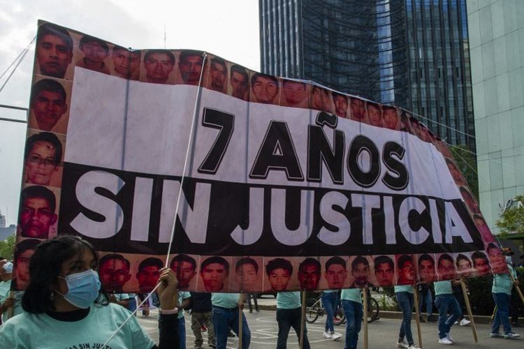 Orang-orang memegang spanduk bertuliskan 7 tahun tanpa keadilan selama protes di Mexico City pada 26 September 2021, untuk menandai tujuh tahun hilangnya 43 siswa dari sekolah pelatihan mengajar di Ayotzinapa.