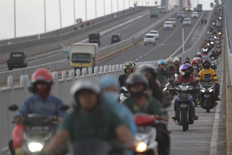 Pengendara motor melintas di Jembatan Suramadu, Surabaya, Jawa Timur, Sabtu (30/4/2022). Pada H-2 Hari Raya Idul Fitri 1443 H,  jembatan yang menjadi penguhubung antara Pulau Jawa dan Pulau Madura tersebut mulai dipadati kendaraan terutama roda dua yang mudik menuju ke Pulau Madura.