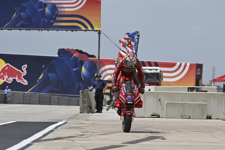 Jack Miller kibarkan bendera Nicky Hayden pada MotoGP Amerika 2022.   Mirco Lazzari gp/Getty Images/AFP (Photo by Mirco Lazzari gp / GETTY IMAGES NORTH AMERICA / Getty Images via AFP)