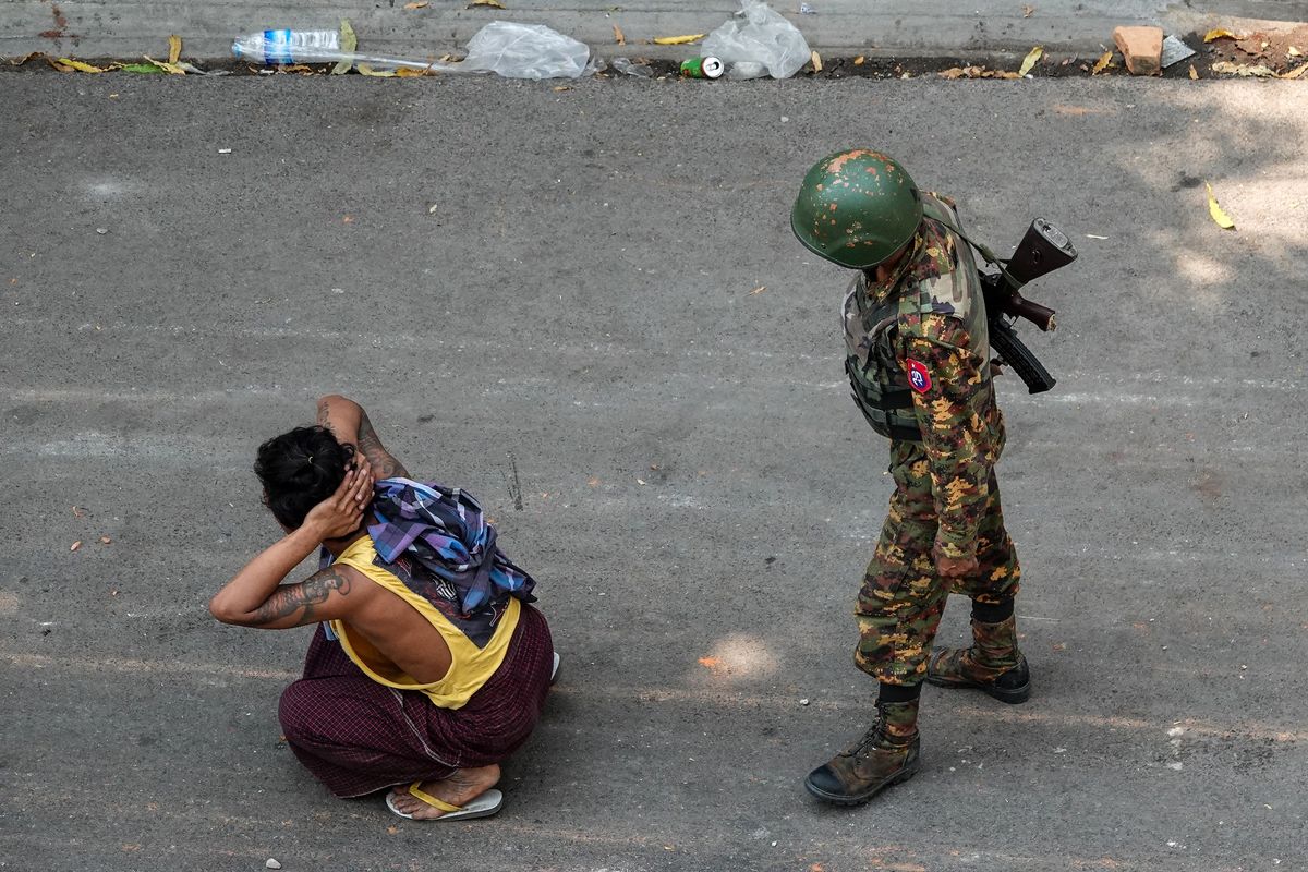 Seorang tentara berdiri di belakang seorang pria yang ditahan, dalam demonstrasi menentang kudeta di Mandalay, Myanmar, pada 3 Maret 2021.