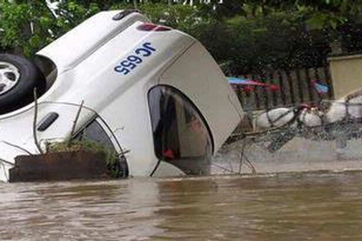 APES - Hujan deras dan drainase Jakarta yang buruk mengakibatkan banjir, hingga membalik sebuah taksi di Jakarta Barat. 