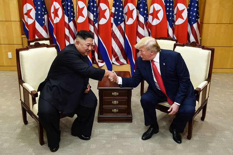 Pemimpin Korea Utara Kim Jong Un (kiri) dan Presiden AS Donald Trump berjabat tangan dalam sebuah pertemuan di wilayah keamanan bersama (JSA) Panmunjom di zona demiliterisasi (DMZ) Korea, Minggu (30/6/2019). Kedatangan Trump ke zona demiliterisasi Korea awalnya diagendakan untuk pertemuan dengan Presiden Korea Selatan Moon Jae-in, namun Presiden Moon mengatakan fokus akan lebih kepada pertemuan Trump dengan Kim Jong Un.