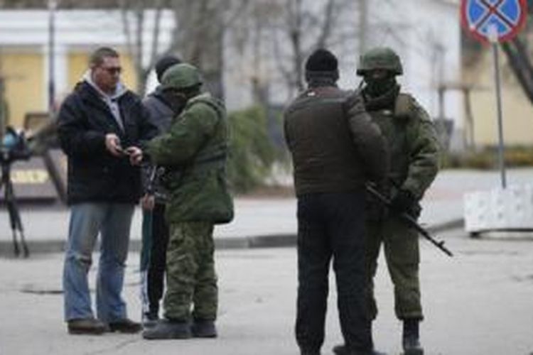 Tentara Rusia memeriksa wartawan di kota Simferopol, semenanjung Crimea. Rusia dipandang terburuk karena melakukan intervensi di Ukraina.