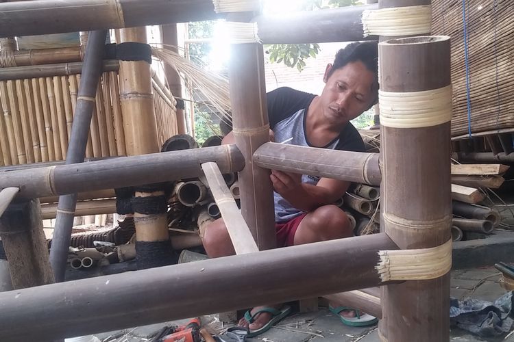 Murdi sedang mengencangkan ikat tempat duduk dari bambu