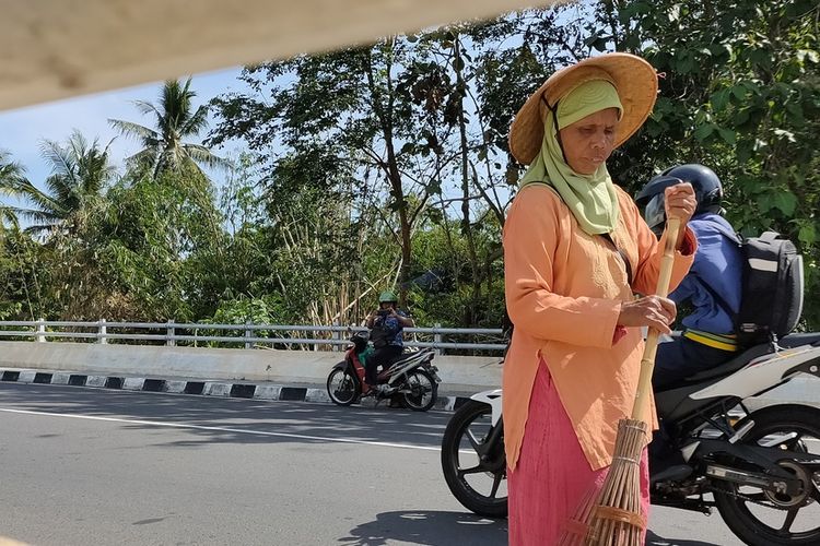 Partiyem (57) sedang menyapu jalan layang Ngelo di Kapanewon (kecamatan) Sentolo, Kulon Progo, DI Yogyakarta. Banyak dermawan bermobil singgah sebentar sekadar untuk memberi santunan sebagai dukungan atas aksi tak lelah nenek tujuh orang cucu ini.