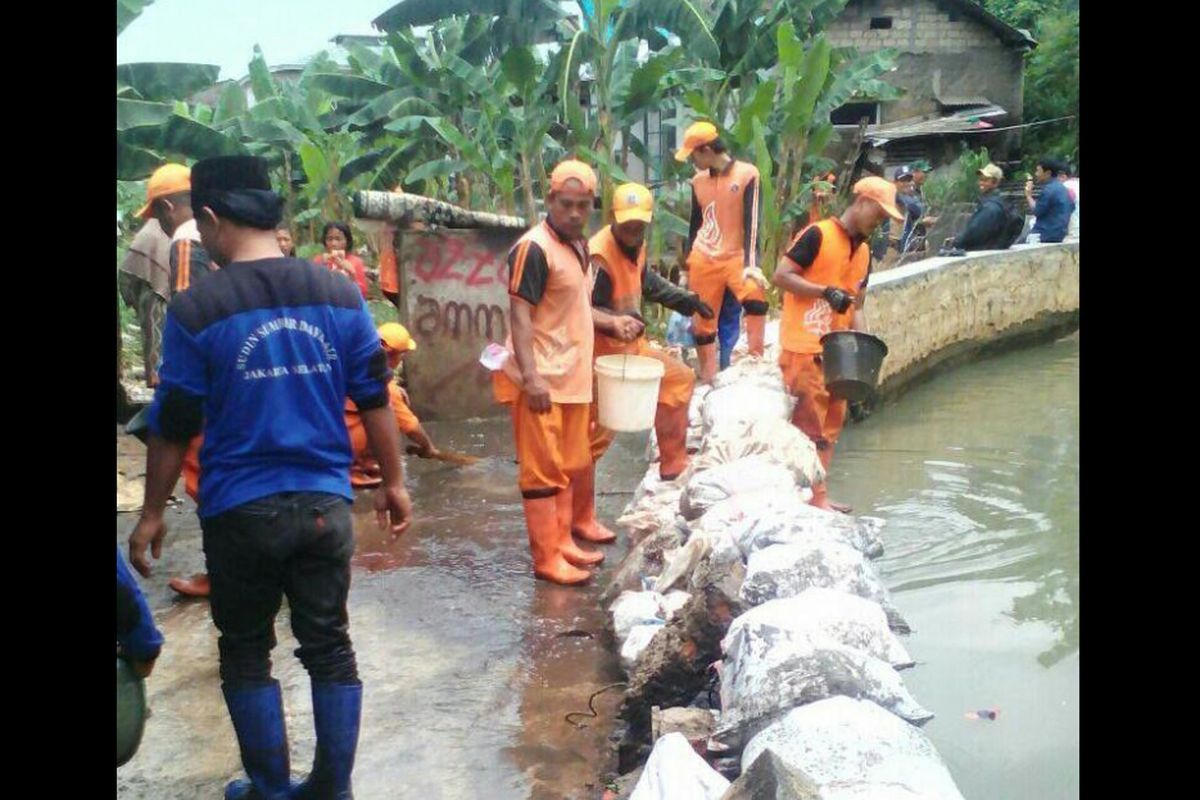 Petugas PPSU bergotong-royong memperbaiki tanggul.