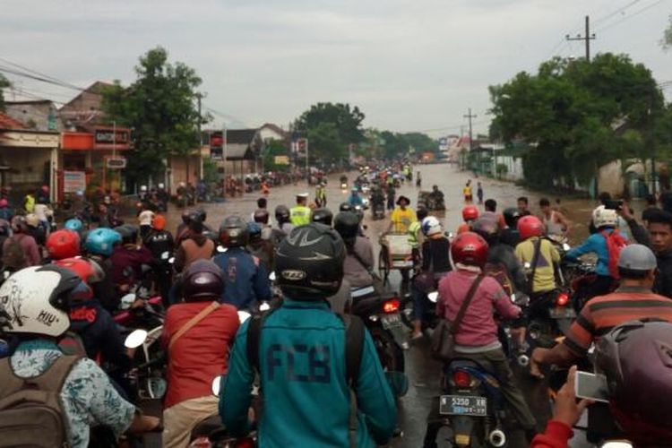 Ratusan pengendara motor yang mengantri sekaligus menunggu surutnya genangan air di Desa Tambakrejo Kecamatan Kraton untuk melintas di jalur Pantura Pasuruan-Probolinggo