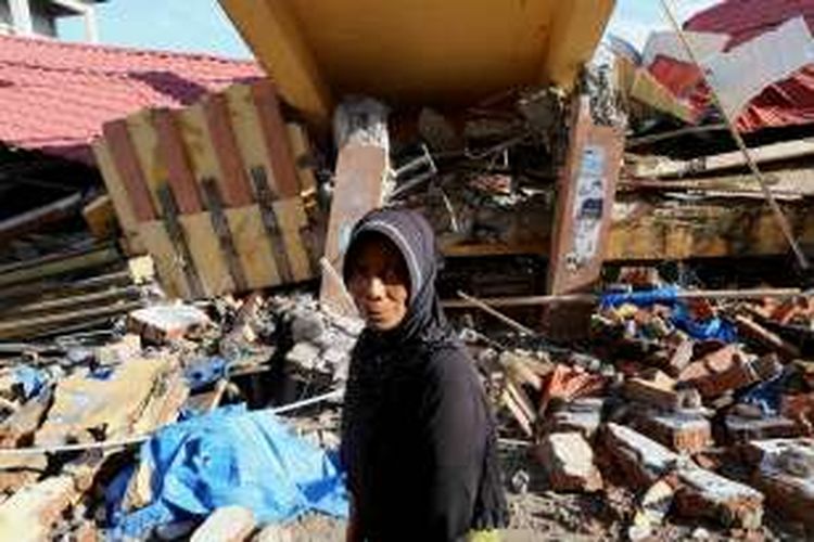 Warga melintasi bangunan pasar Meureudu yang roboh akibat bencana gempa di Kecamatan Meureudu, Kabupaten Pidie jaya, Aceh, Kamis, (8/12/2016). Sebagian korban sudah teridentifikasi dan sebagian lagi masih dalam proses pendataan serta korban luka sendiri berjumlah 128 orang luka berat, dan 489 orang luka ringan, 86 unit rumah, 105 ruko, 13 unit masjid rusak berat.