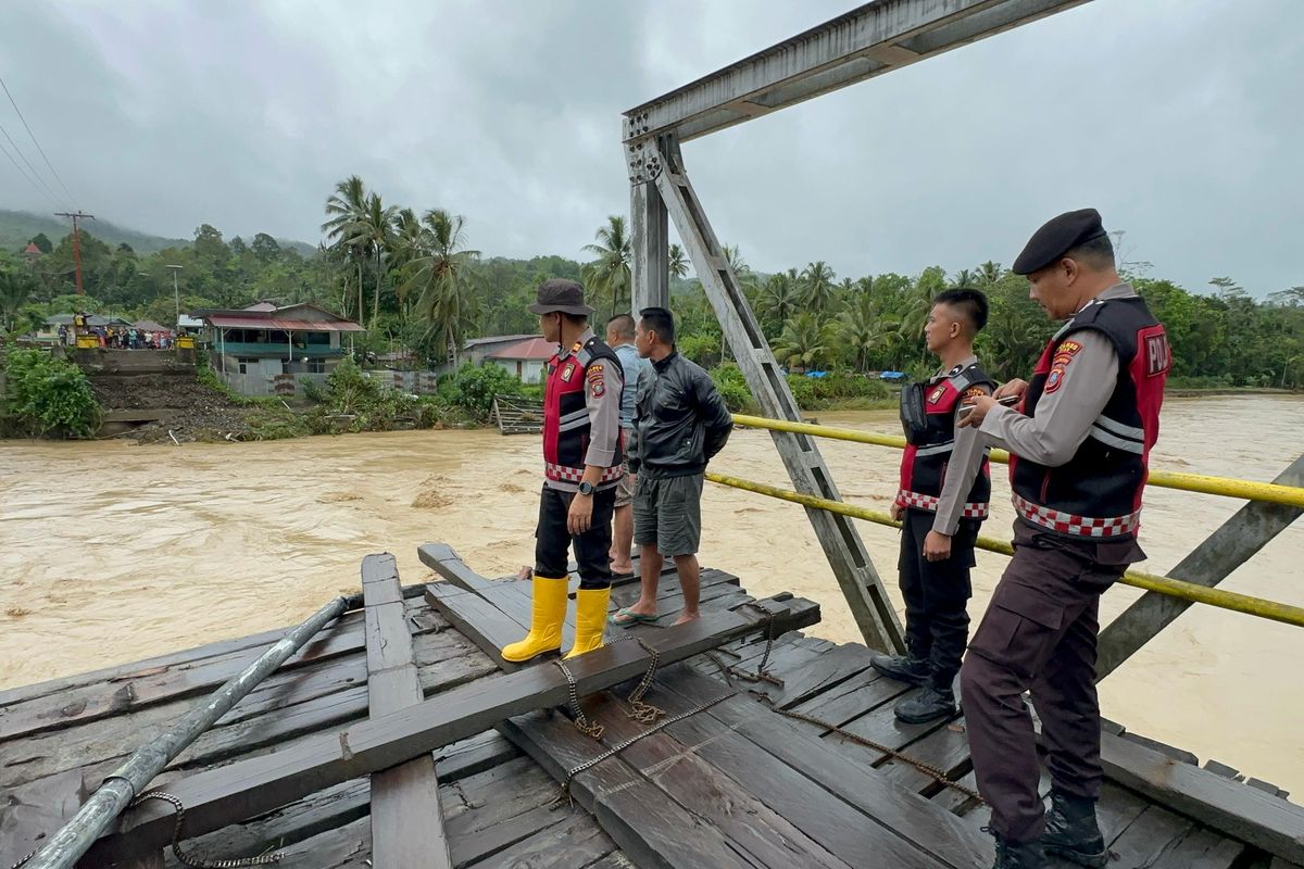 Polisi berjaga di Jembatan Noyo di Kecamatan Mandrehe, Kabupaten Nias Barat, Sumatera Utara, yang  roboh diterjang banjir pada Rabu (5/3/2025)