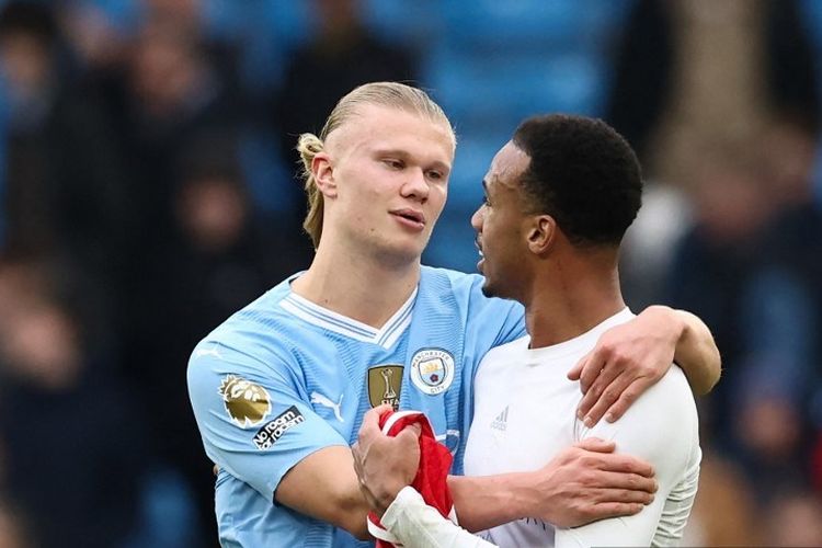 Erling Haaland dan Gabriel Magalhaes berpelukan usai sempat terlibat adu mulut usai laga pekan ke-30 Liga Inggris 2023-2024 antara Man City vs Arsenal di Stadion Etihad, Minggu (31/3/2024). (Photo by Darren Staples / AFP)