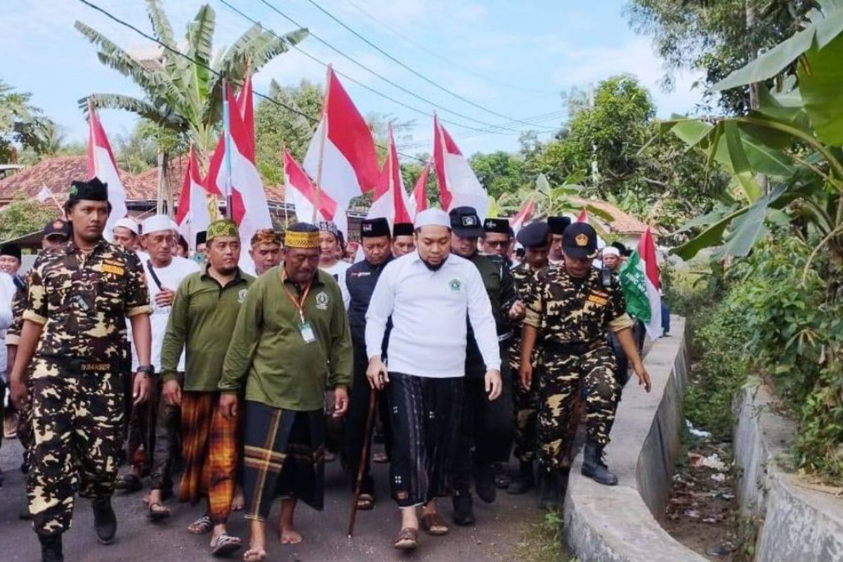 KH. Raden Azaim Ibrahimy berkaos putih memegang tongkat saat napak tilas perjuangan pahlawan nasional KH. As'ad Syamsul Arifin dari Pondok Pesantren Sumber Gayam Pamekasan ke tempat persembunyian Kiai As'ad di Dusun Kadur Atas, Kecamatan Kadur, Kabupaten Pamekasan, Rabu (10/8/2022).