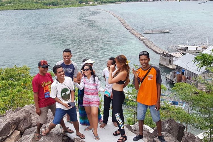 Para wisatawan berswafoto di bukit dan jembatan batu di Pulau Kojadoi, Kabupaten Sikka, Flores, NTT, Senin (3/6/2019).