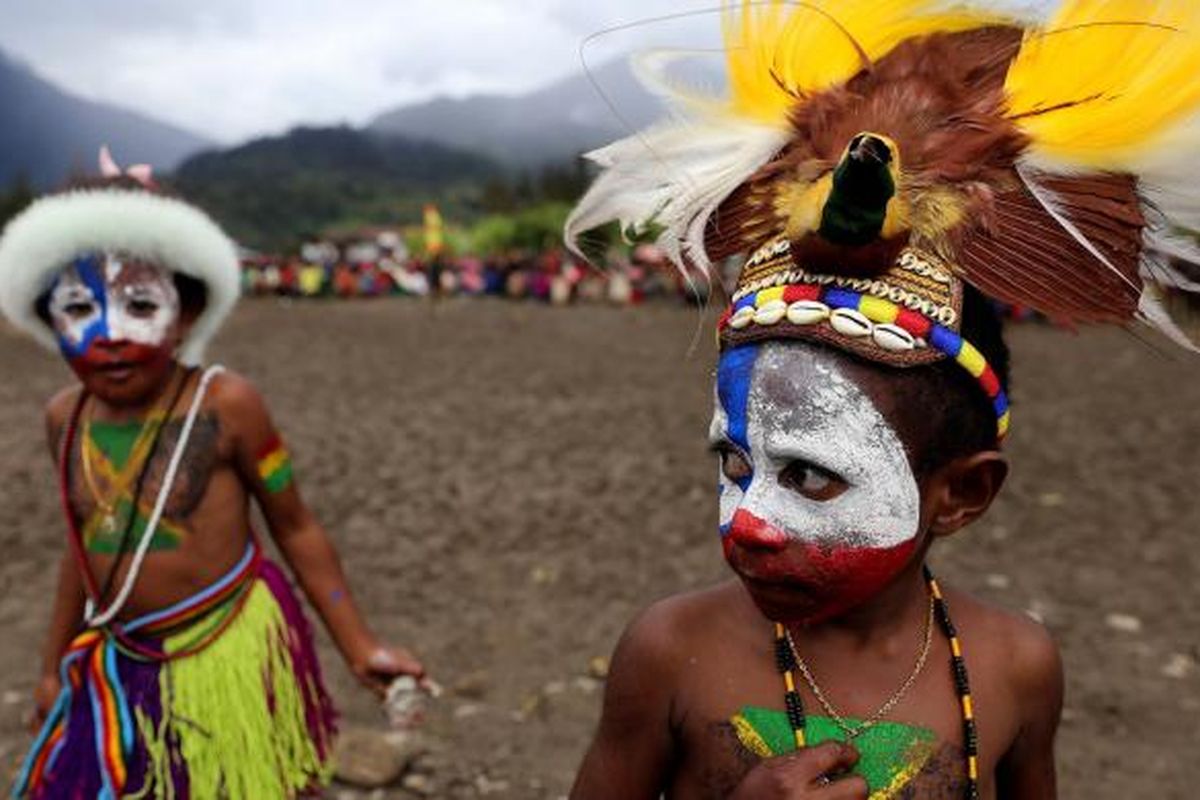 Anak kecil berpose saat menghadiri upacara adat bakar batu di Lapangan Trikora, Distrik Ilaga, Kabupaten Puncak, Papua, Kamis (15/9/2016). Tradisi bakar batu merupakan salah satu tradisi terpenting di Papua yang berfungsi sebagai tanda rasa syukur, menyambut tamu, atau acara perdamaian setelah perang antar suku.