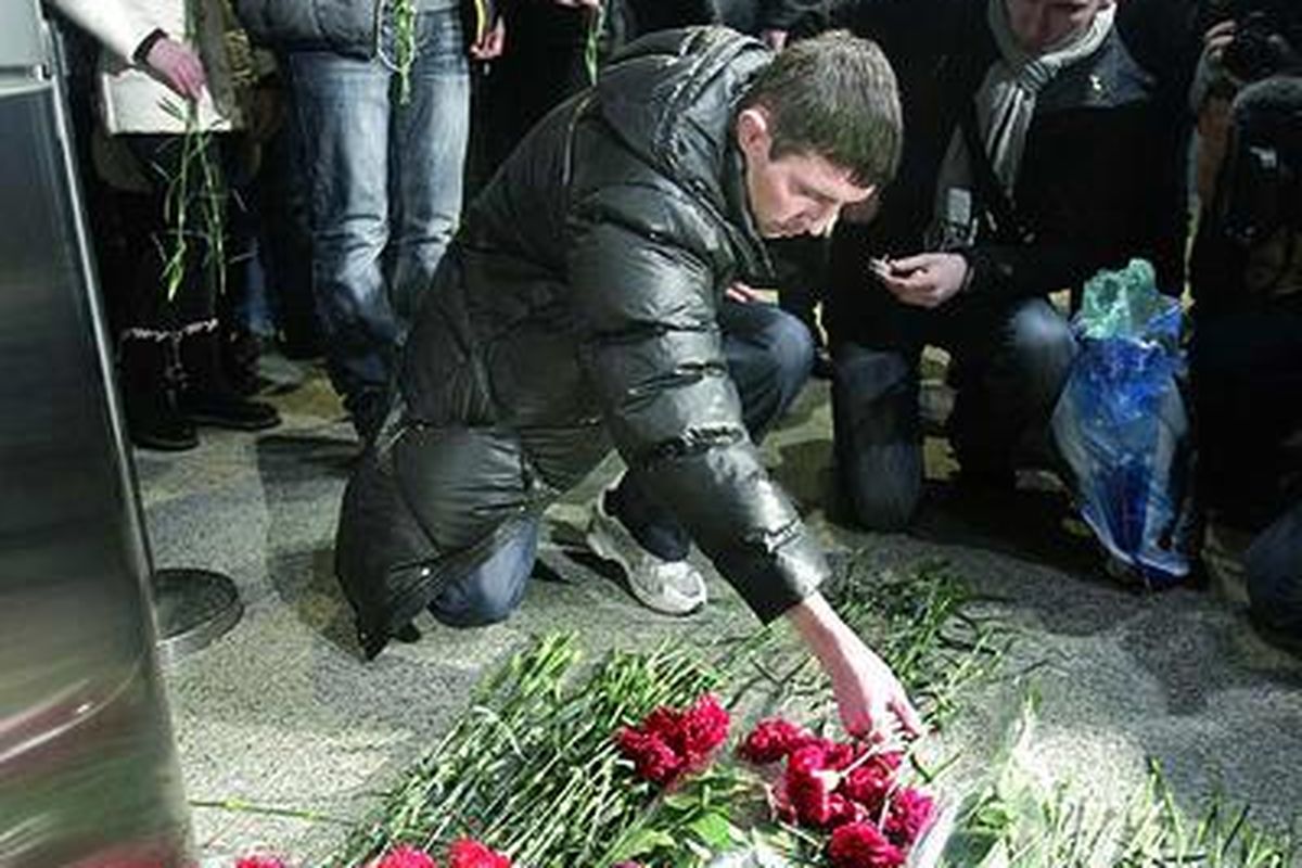 Orang-orang meletakkan bunga di tempat ledakan di Bandara Domodedovo, Moskwa, Rusia, Selasa (25/1), sementara yang lainnya menunggu pemeriksaan keamanan sebelum memasuki bandara. Pengamanan bandara diperketat setelah terjadi aksi bom bunuh diri yang memakan korban jiwa ini.