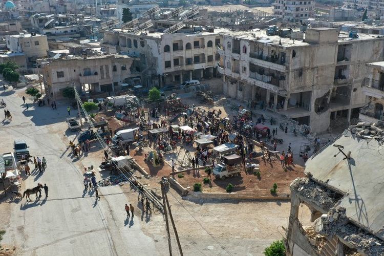 Sebuah foto udara menunjukkan kerumunan di tempat pameran di dekat bangunan yang rusak, untuk Idul Adha yang dirayakan oleh umat Islam di seluruh dunia, di kota Binnish Suriah di provinsi Idlib yang dikuasai pemberontak di barat laut, pada 9 Juli 2022.