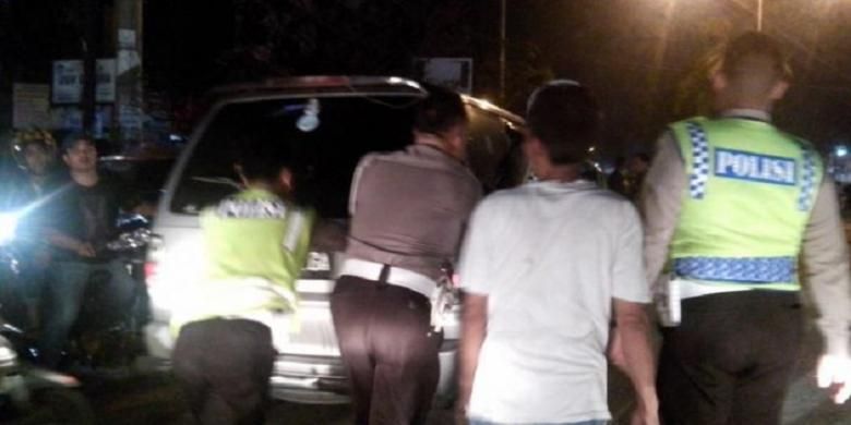 Petugas kepolisian mendorong mobil yang diduga penyebab kemacetan di Jalan Jamin Ginting, Selasa (30/6/2015) malam 