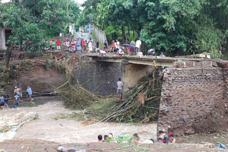 Warga Desa Banjaragung, Kecamatan Bareng, Kabupaten Jombang, Jawa Timur, membersihkan sampah yang tersangkut di kolong jembatan Sungai Pakel, Selasa (2/2/2021). Jembatan terputus akibat banjir bandang, pada Senin malam.