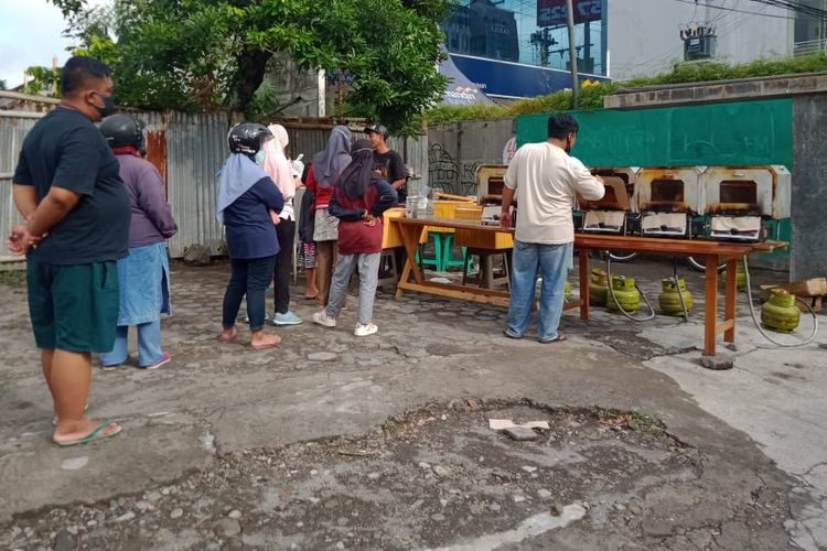 Penjual sedang mengecek roti dalam oven. 