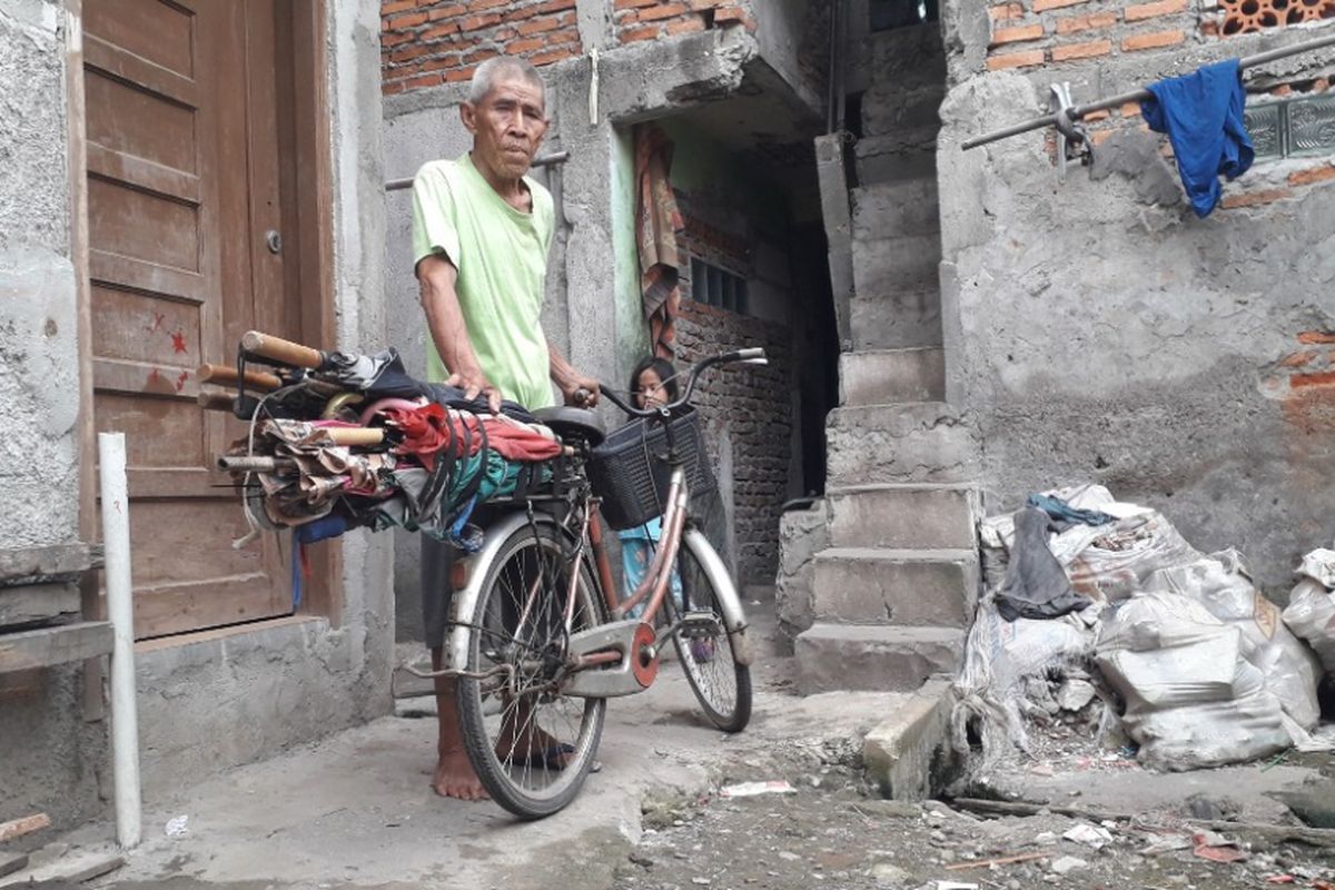 Kong Muin berpose di depan sepedanya yang ia gunakan dalam menjajakan keahliannya sebagai tukang servis payung, Jumat (1/2/2019).