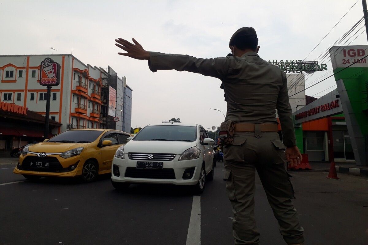 Petugas gabungan dari Satpol PP Kota Bogor sedang memutarbalikkan kendaraan yang melanggar aturan ganjil genap di titik check point Simpang Denpom, Sabtu (1/5/2021).