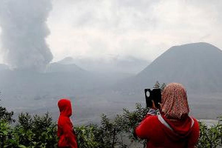 Wisatawan menyaksikan erupsi Gunung Bromo dari Desa Ngadisari, Kecamatan Sukapura, Kabupaten Probolinggo, Kamis (17/12/2015). Walaupun masih bisa melihat dari jarak di luar 2,5 kilometer dari Gunung Bromo dan melihat matahari terbit, terkait status Siaga Gunung Bromo membuat wisatawan yang berkunjung turun drastis hingga 90 persen. 