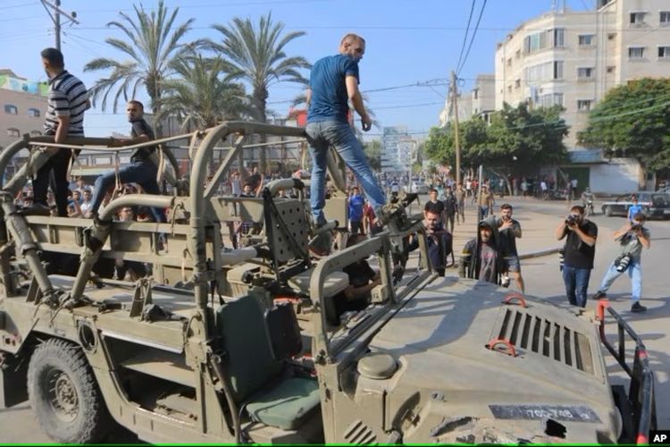 Warga Palestina mengendarai kendaraan militer Israel yang diambil dari pangkalan militer yang dikuasai militan Hamas di dekat pagar Jalur Gaza, di Kota Gaza, Sabtu, 7 Oktober 2023.