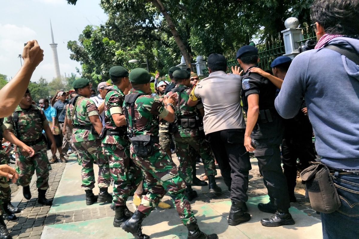 Peserta aksi dari Aliansi Mahasiswa Anti Rasisme, Kapitalisme, Kolonialisme dan Militerisme, dorong-dorongan dengan polisi-TNI di seberang Gedung Kementerian Dalam Negeri (Kemendagri), Jalan Medan Merdeka Utara, Jakarta Pusat, Kamis (22/8/2019).